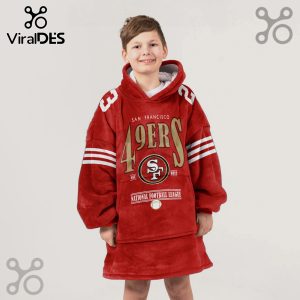 A young child wears an oversized, red hoodie blanket with San Francisco 49ers graphics.!