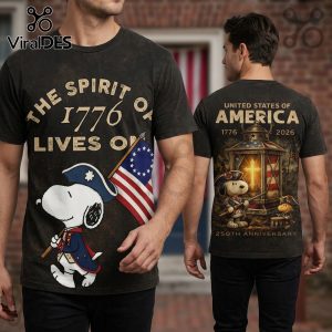 Gray tee featuring Snoopy in retro cartoon style with the text: THE SPIRIT OF 1776 LIVES ON!