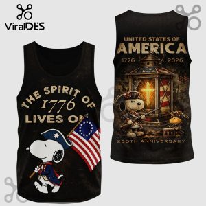 Black tank top with cartoon Snoopy as a patriot holding a flag. Text: THE SPIRIT OF 1776 LIVES ON, UNITED STATES OF AMERICA.!