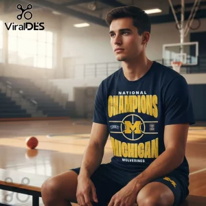 Navy blue collegiate t-shirt with bold yellow and white text: NATIONAL CHAMPIONS INDY M MICHIGAN WOLVERINES COMING HOME!