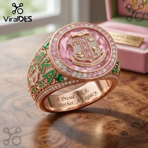 Rose gold sorority ring with pink faceted stone, AKA crest, green AKA letters, white gems! Text 'A Proud AKA. A Mother. A Legacy.'!