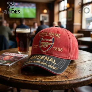Red and black Arsenal FC baseball cap with embroidered logo, EST 1886 text, and personalized name space on a pub table!