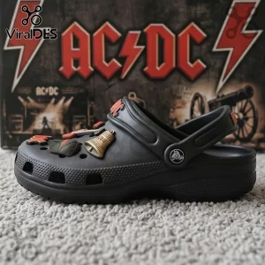 Black Crocs featuring red AC/DC band logo Jibbitz, a green military hat, and a gold bell with 