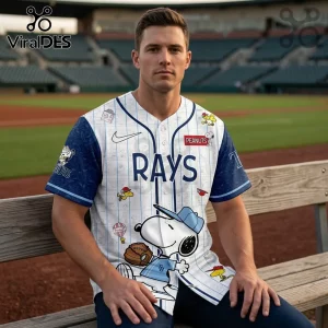 Man wearing white Tampa Bay Rays baseball jersey with blue pinstripes and Peanuts character Snoopy graphics on a bench.!