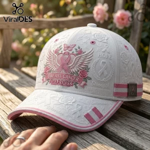 White baseball cap with pink embroidered wings, ribbon, floral patterns, and text reading Breast Cancer Awareness.!