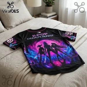 Black baseball jersey with K-POP DEMON HUNTER text, pink moon, and three anime-style silhouettes over a cityscape.!