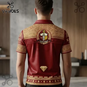Maroon polo shirt with gold Greek key patterns and a central fraternity crest, featuring a small diamond icon at the hem.!
