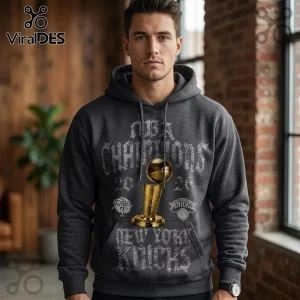 Charcoal gray hoodie featuring New York Knicks 2026 NBA Champions graphics with a golden Larry O'Brien trophy illustration.!