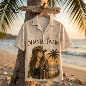 Shania Twain button-up beige beach shirt with leopard print hat design and palm tree sunset graphic on wooden hanger.!