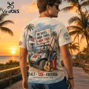 Man wearing a cream graphic t-shirt featuring a beach jeep, surfboard, guitar, and sunset landscape text art.!