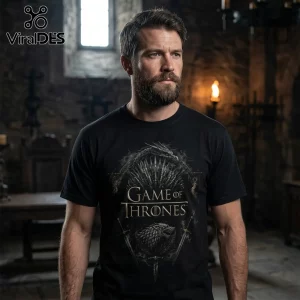 Man wearing a black t-shirt with a metallic Game of Thrones logo, iron throne graphic, and wolf sigil in a stone room.!
