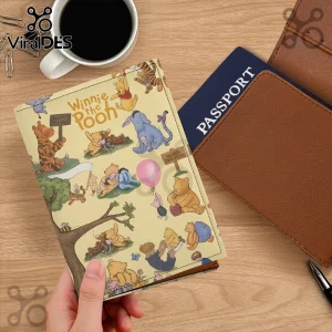 Winnie the Pooh themed faux leather passport cover with cream background and illustrated characters on a wooden desk.!