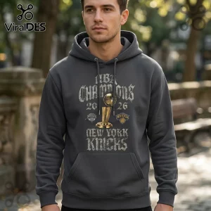 Dark grey hoodie featuring an NBA Champions 2026 graphic with a gold Larry O'Brien trophy and New York Knicks logo.!