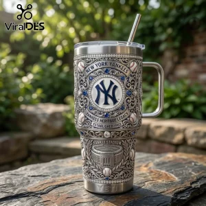 Silver stainless steel tumbler with engraved New York Yankees logo, blue gems, stadium relief, and straw on stone surface.!