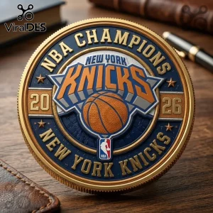 Round commemorative New York Knicks 2026 NBA Champions coin with gold, blue, and orange metallic relief on wood surface.!