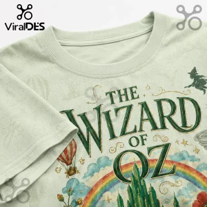 Light green graphic t-shirt featuring The Wizard of Oz title, rainbow, Emerald City, hot air balloon, and witch silhouette.!