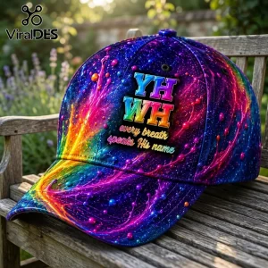 Baseball cap with vibrant galaxy print, neon paint splatters, and text YHWH every breath speaks His name on a bench.!