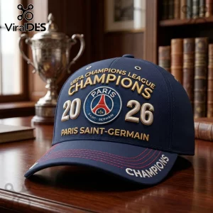 Navy blue PSG baseball cap with gold Champions 2026 embroidery and Paris Saint-Germain club logo on a wood desk.!