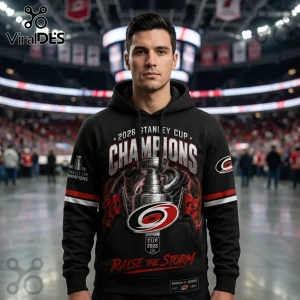 Man wearing black hoodie with 2026 Stanley Cup Champions graphic, Carolina Hurricanes logo, and Raise the Storm text.!