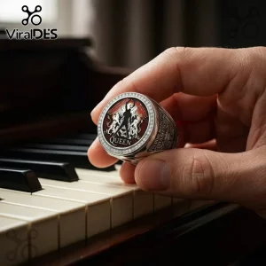 Silver Queen band ring with red enamel crest and white stones held by fingers over piano keys.!