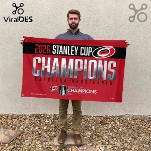 Man holding a red and black Carolina Hurricanes 2026 Stanley Cup Champions flag featuring team and NHL branding.!