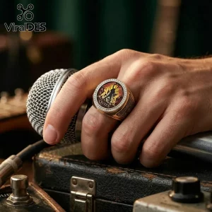 Gold Queen band logo ring with crest motif and cubic zirconia border worn on hand holding a silver stage microphone.!