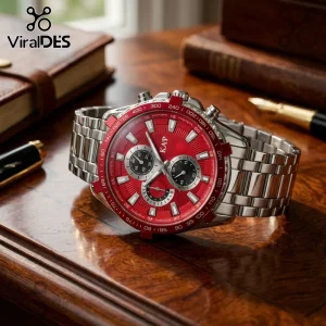 Silver stainless steel chronograph watch with a bright red dial and tachymeter bezel resting on a dark wooden desk.!