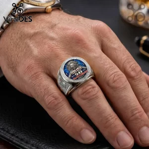 Silver metal Iron Maiden 50th anniversary ring with Eddie character, blue background, and cubic zirconia border on finger.!