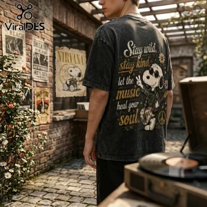 Charcoal acid-wash t-shirt with Snoopy playing guitar, text reads Stay wild, stay kind, let the music heal your soul.!