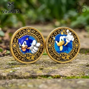 Two gold-colored Sonic the Hedgehog 35th anniversary commemorative coins with blue enamel centers on a stone background.!