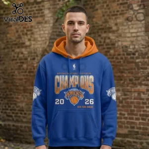 Man wearing a blue New York Knicks 2026 Champions hoodie with orange hood, NBA logo, and printed team graphics.!