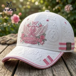White baseball cap featuring embroidered pink breast cancer awareness ribbon, roses, wings, and text on a wooden surface.!
