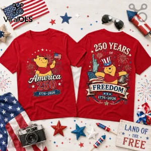 Red graphic t-shirts with Winnie the Pooh, patriotic text, American flags, and fireworks, flat laid on a white surface.!