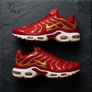 Nike Air Max Plus sneakers in red and gold with white midsoles and visible air units on a dark grey slate background.!