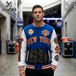 Man wearing blue and white New York Knicks varsity jacket with city skyline detail and championship embroidery patches.!