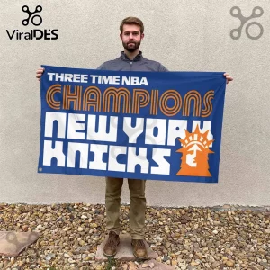 Man holding a blue New York Knicks banner with orange text reading Three Time NBA Champions and a Statue of Liberty icon.!