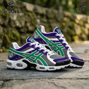 Custom sneakers with grey mesh, purple accents, and green graphic overlays featuring a tribal mask logo on stone pavement.!