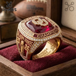 Gold Oklahoma Sooners 2026 NCAA championship ring with a large red center stone, diamond accents, and etched text details.!