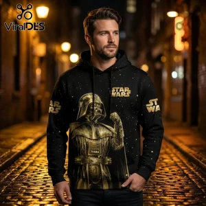 Man wearing a black hoodie with a gold Darth Vader graphic and Star Wars logo, set against a star-patterned background.!