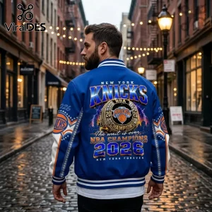 Man wearing blue New York Knicks championship varsity jacket with 2026 graphic print, championship ring, and NYC logo detail.!