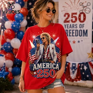 Woman wearing oversized red t-shirt featuring a rockstar graphic, US flag, and America 250 text with fireworks backdrop.!