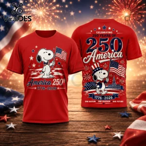 Red T-shirt with Snoopy character holding US flag, celebrating America's 250th anniversary, 1776-2026, on wood background.!