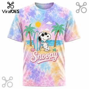Snoopy wearing sunglasses with a surfboard on a sandy beach, printed on a pastel blue, pink, and yellow tie-dye T-shirt.!