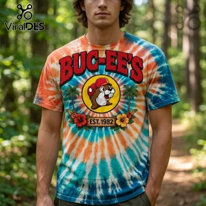 Buc-ee's logo graphic on a vibrant orange and teal tie-dye t-shirt featuring a beaver mascot, palm trees, and flowers.!