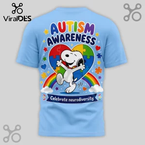 Light blue t-shirt with Snoopy jumping in front of a colorful puzzle piece heart, rainbow, and Autism Awareness text.!
