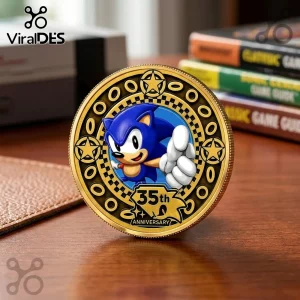 Gold-colored Sonic the Hedgehog 35th Anniversary collector coin with a star-patterned border on a wooden desk.!