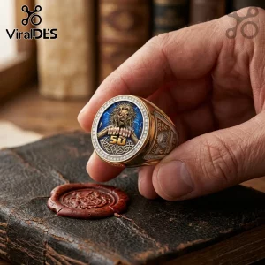 Gold ring featuring Eddie from Iron Maiden, blue enamel, and a number 50, held against a vintage leather-bound book.!