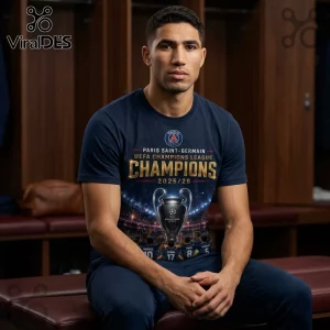Man wearing a navy blue Paris Saint-Germain 2025/26 Champions League t-shirt with a silver trophy graphic in a locker room.!