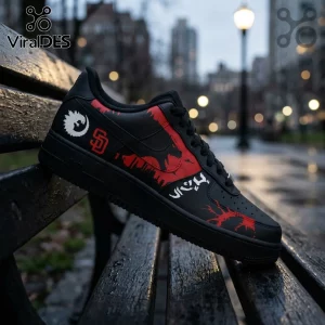 Black sneaker with red splatter pattern, SD logo, and white graphics resting on a wooden park bench.!