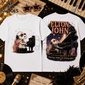White cotton t-shirt with Snoopy graphic dressed as Elton John playing a piano under text reading Elton John.!
